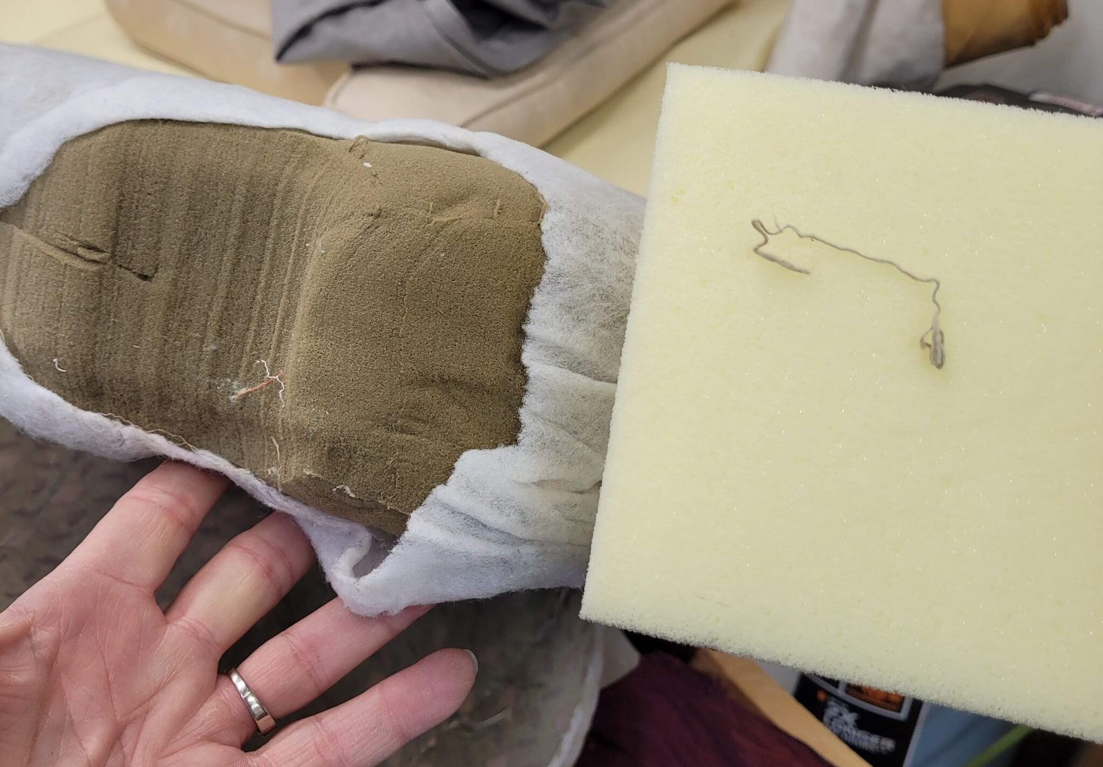 Hand holding a fresh white foam sample against the worn brown foam it replaces
