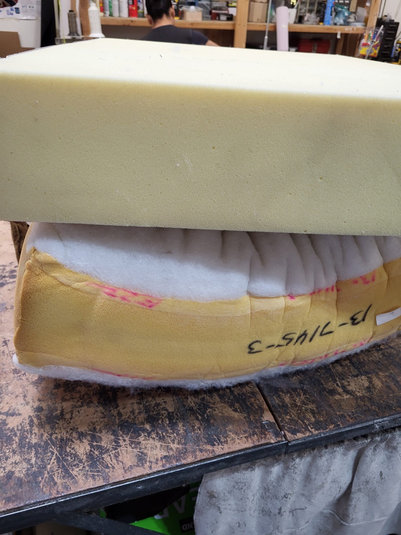 New foam block resting above a marked-up old cushion on a workbench