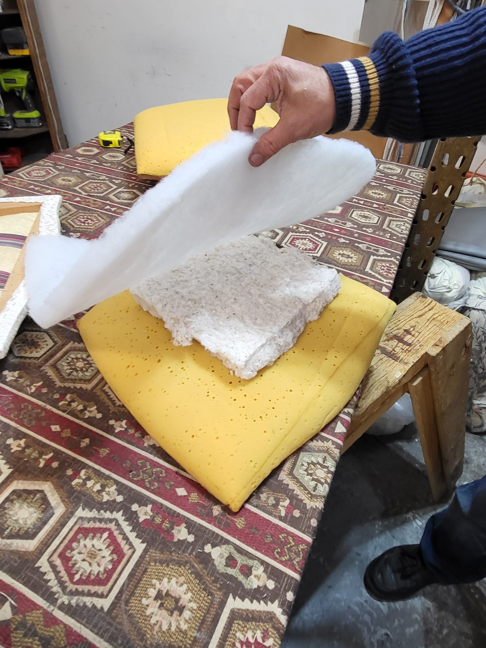 Hand laying white dacron batting over a new yellow foam cushion core