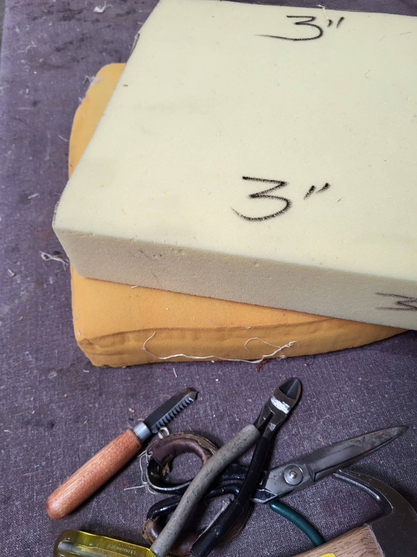 New foam block marked with a three inch measurement beside upholstery hand tools