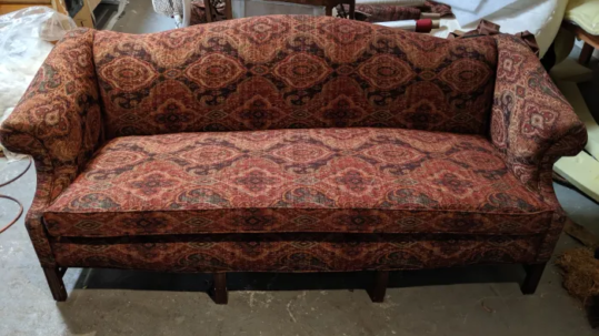 Camelback sofa finished in red and gold tapestry with a restored dark wood base